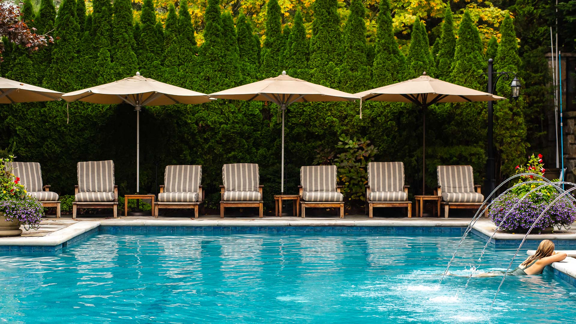 Woman resting at the edge of a serene outdoor pool surrounded by greenery