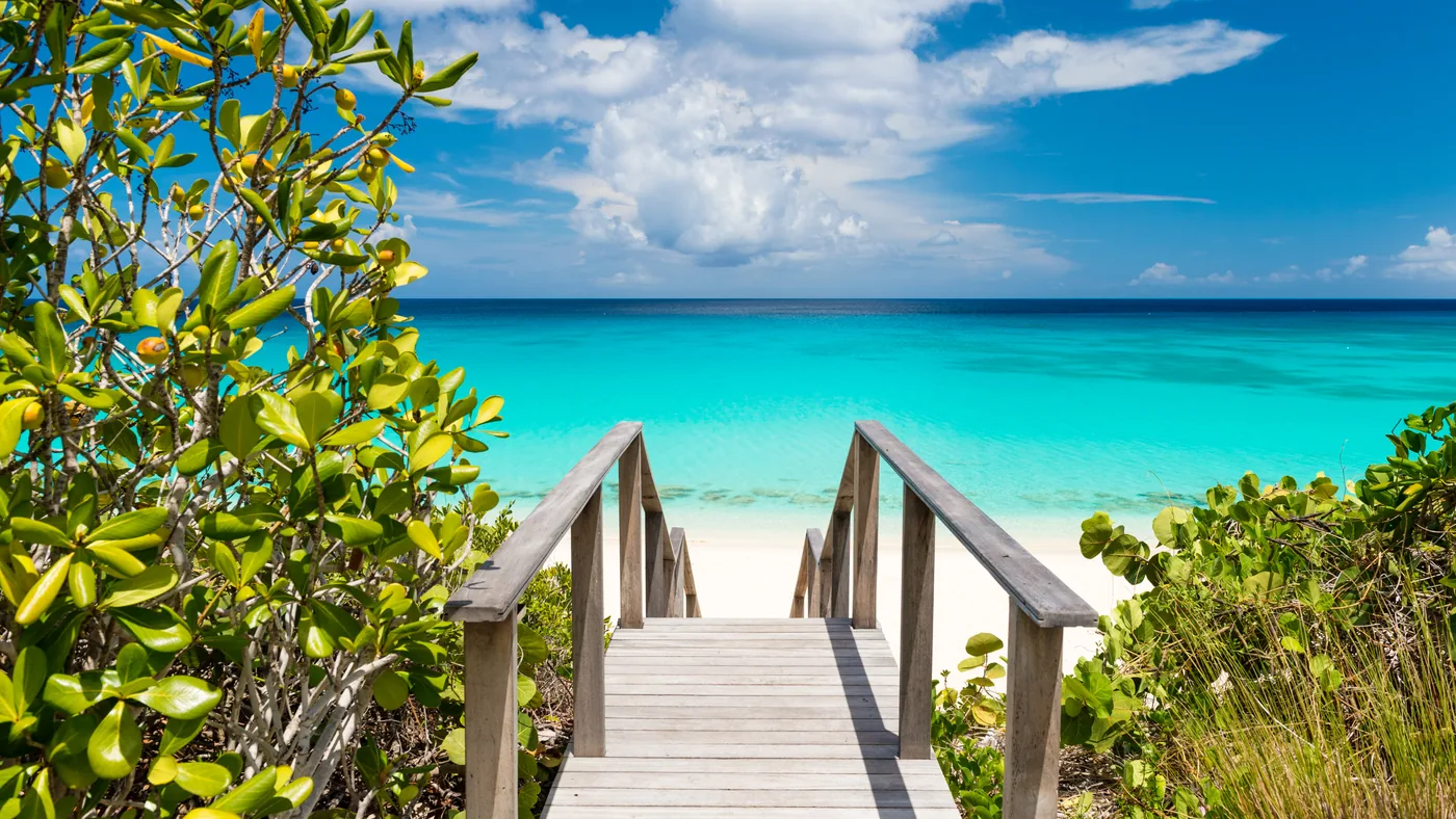 A weathered boardwalk leading down to a bright turquoise beach