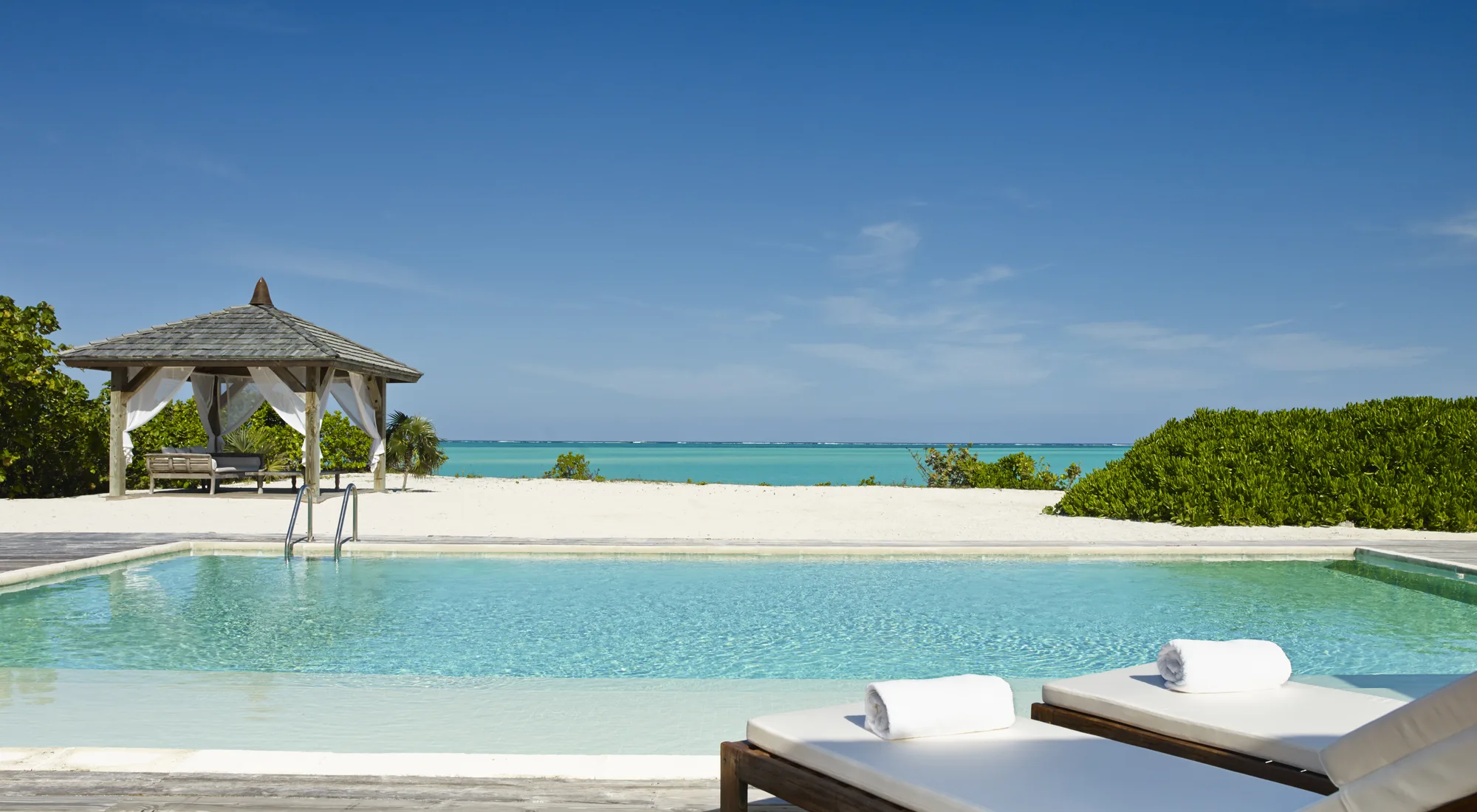 A serene infinity pool at a private villa overlooking tropical greenery and the sea