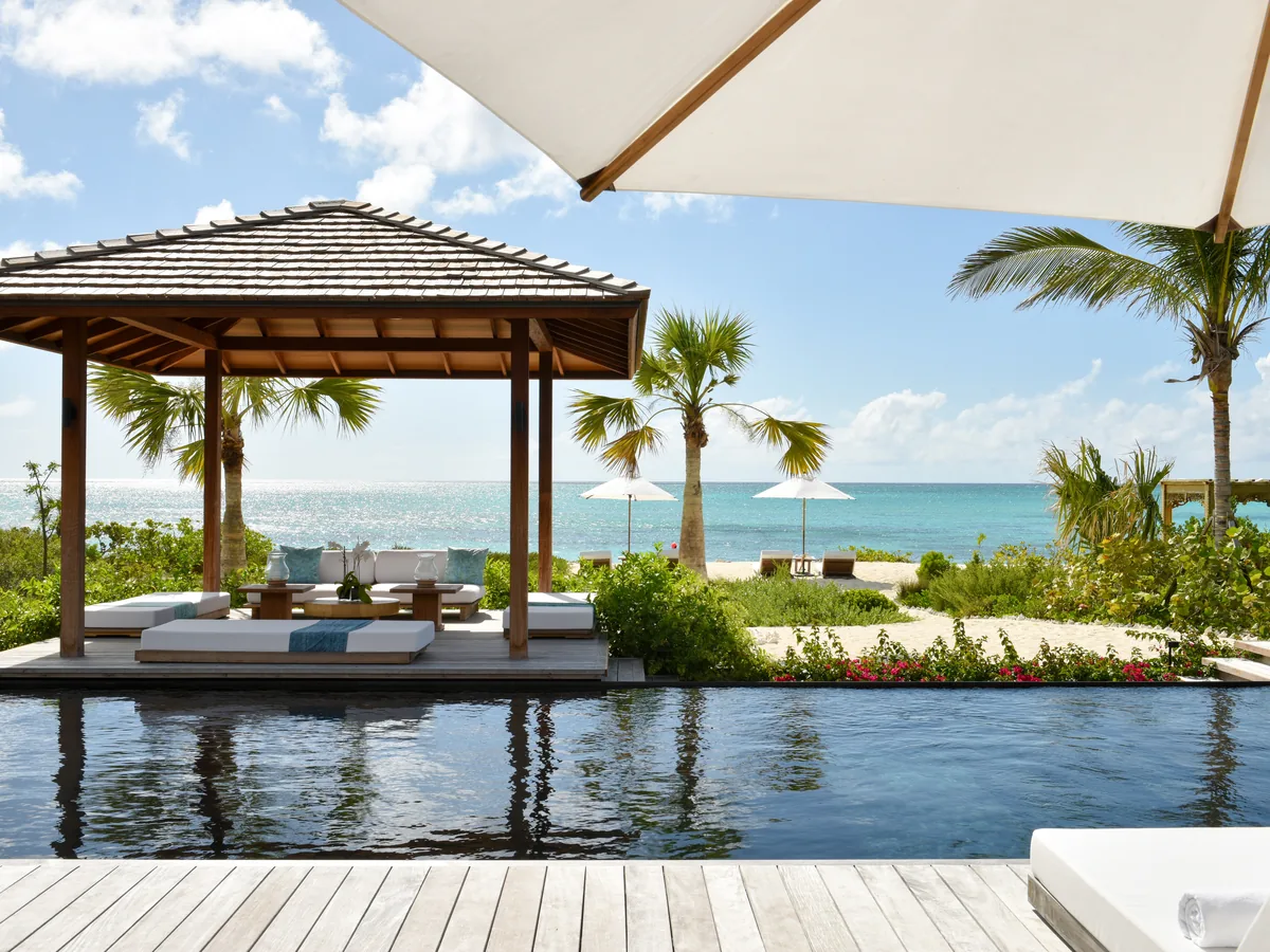 A boutique villa pool and shaded gazebo beside the turquoise sea