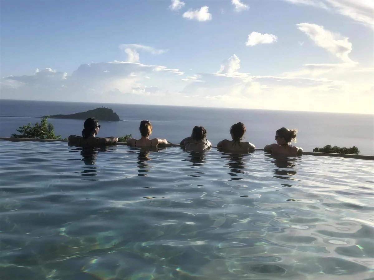 Five retreat guests at the edge of an infinity pool, watching the sea together