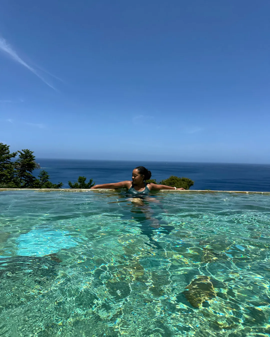 A guest floating at the edge of an infinity pool above the sea