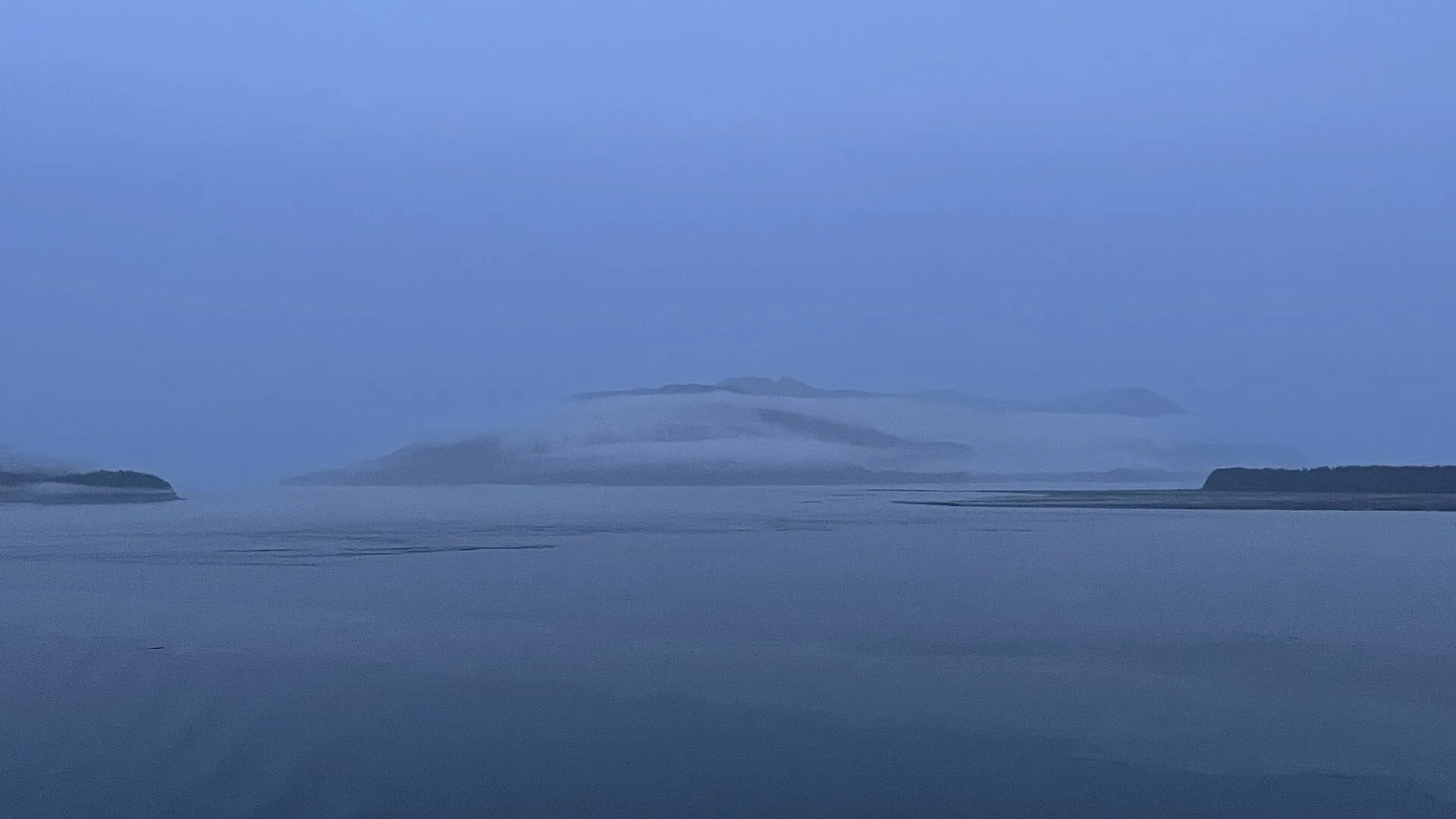 A cruise ship sailing the Inside Passage past forested mountains and calm water in Alaska