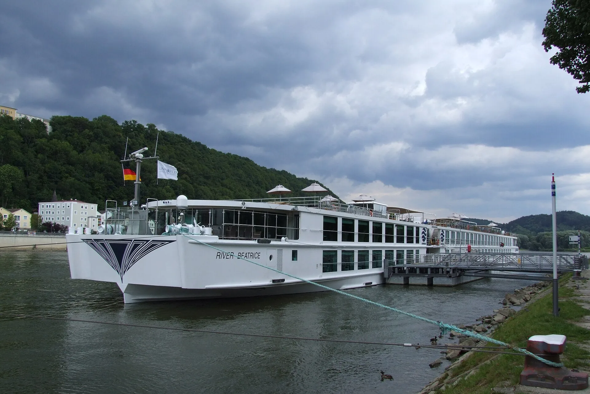 A sleek river cruise ship moored on a European river beside a historic town