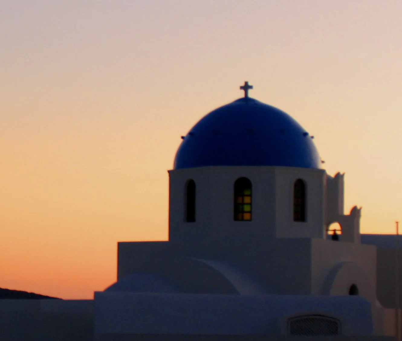 A blue-domed church in Oia, Santorini, at sunset