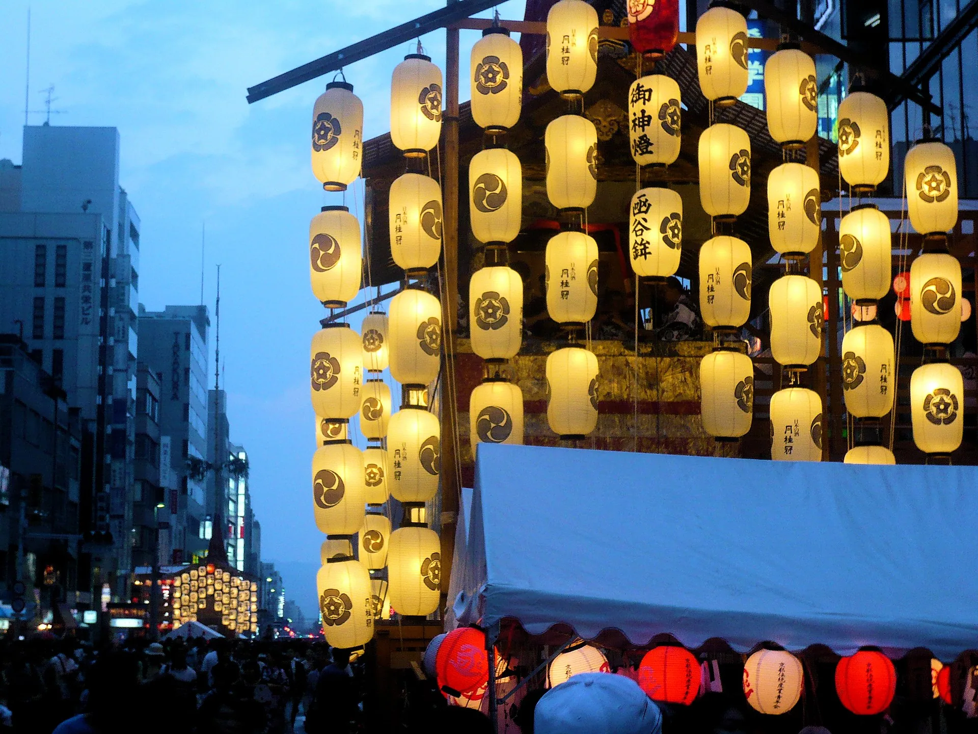 A traditional Kyoto machiya townhouse facade with wooden lattice and hanging sudare screens