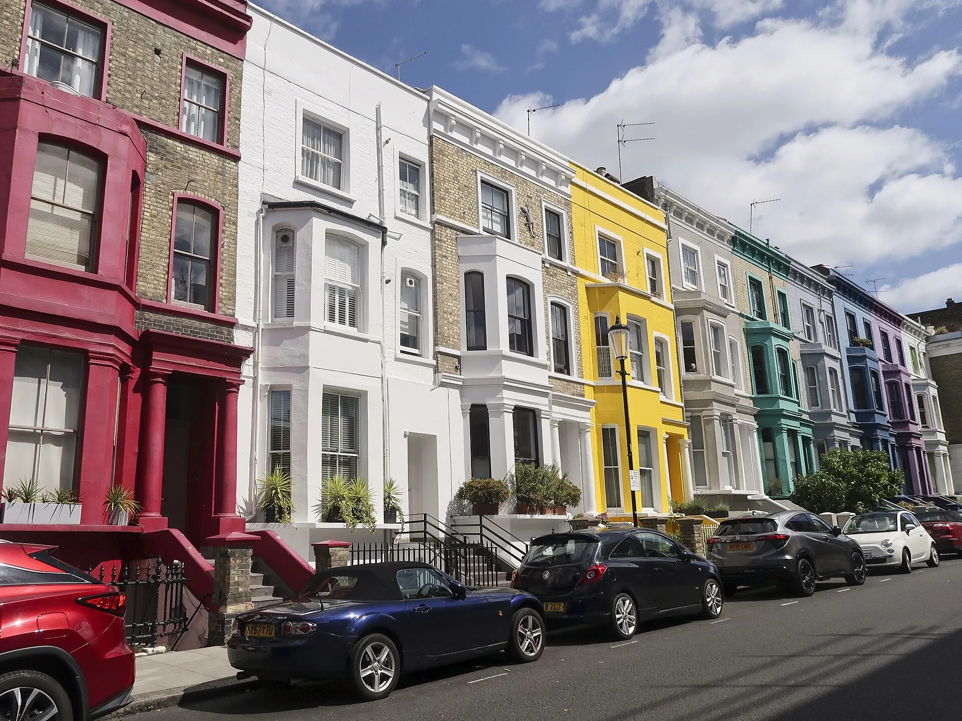 A row of brightly painted pastel townhouses on a street in Notting Hill, London