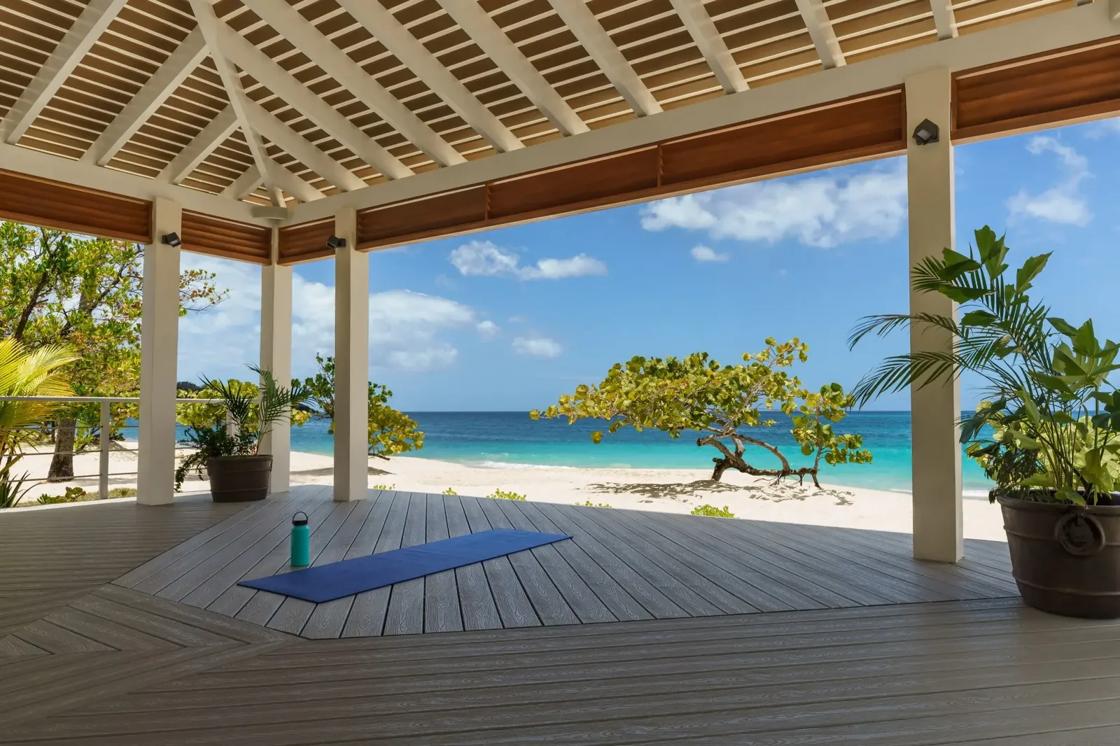 A calm open-air wellness deck facing the sea, set up for yoga at a Caribbean beach resort