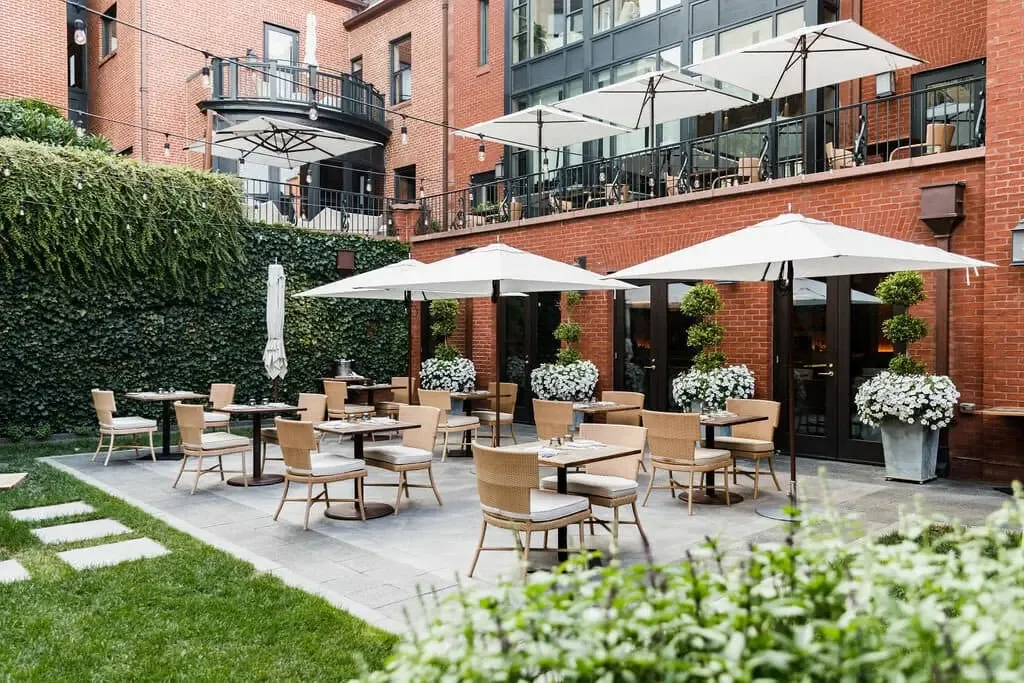 An elegant brick courtyard terrace set for dining at a boutique city hotel