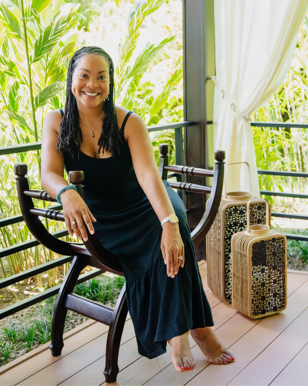 Kay Jones seated on a veranda surrounded by tropical greenery, smiling